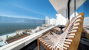 A balcony with wooden chairs, a table, and a view of the sea and mountains. - Muyi Seaview Holiday Homestay (Dali)