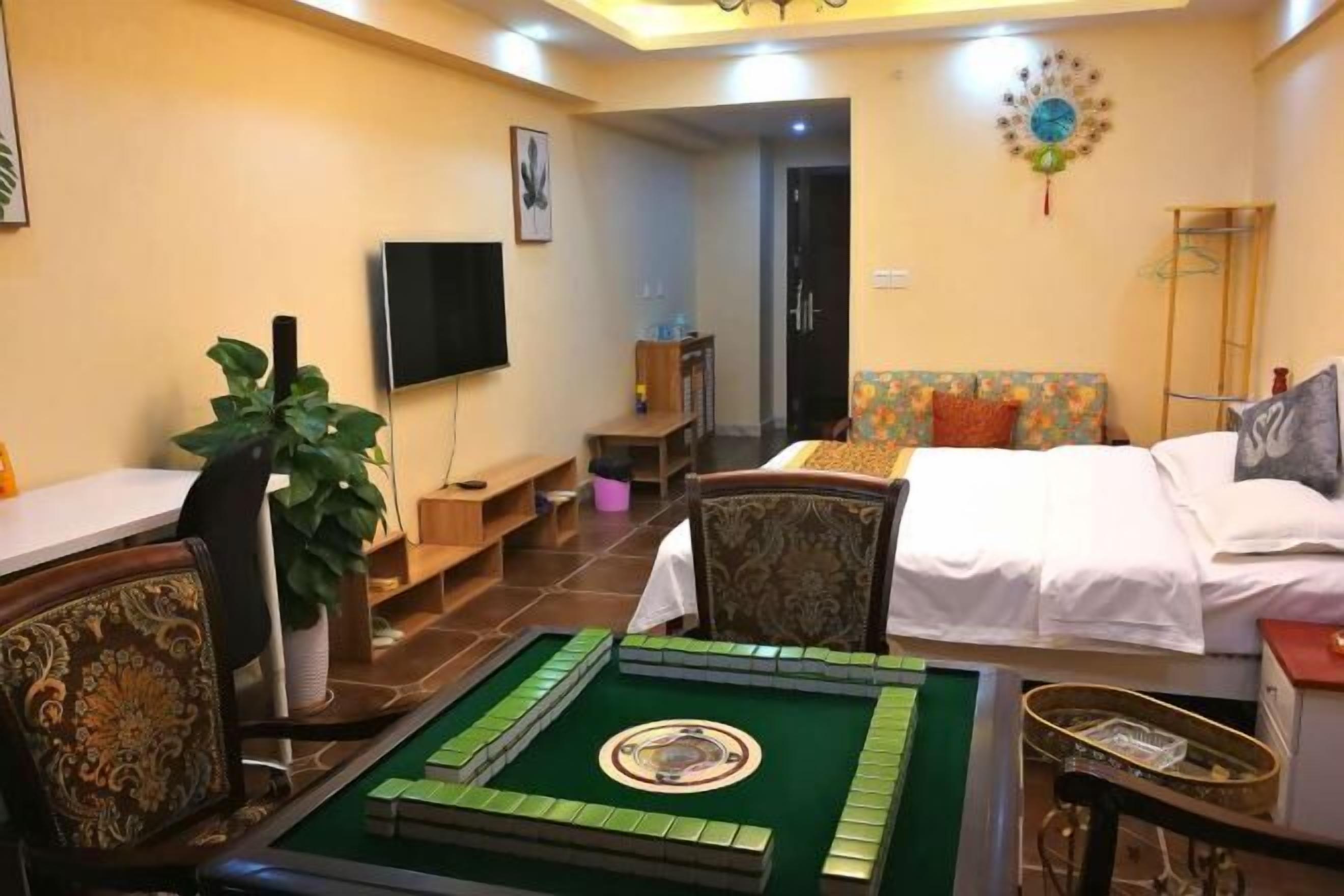 Une chambre d’hôtel avec un lit, une télévision, une petite table avec une plante et un espace recouvert d’une moquette verte.