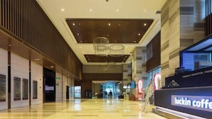 A spacious lobby with a modern design, featuring a coffee shop named 'Luckin Coffee' on the right. - Tuyu Boutique Apartment (Chengdu)