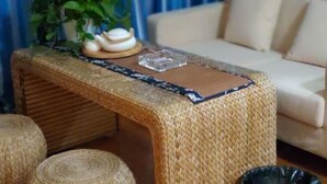 A woven stool with a glass top, placed in front of a sofa. - Tuyu Boutique Apartment (Chengdu)