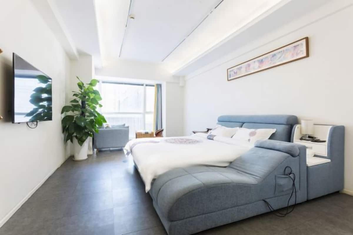 Ein modernes Schlafzimmer mit Bett, Nachttisch und großem Fenster.