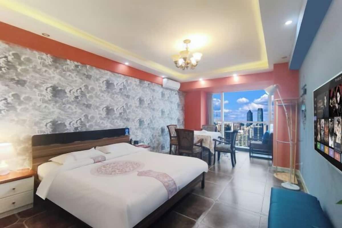 Ein Hotelzimmer mit Steinsturz, einem Bett mit gemustertem Überwurf, einem Schreibtisch mit Stuhl und Blick zum Himmel durch ein Fenster.