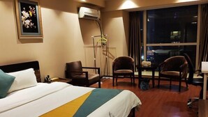A hotel room with a bed, two chairs, a desk, and a window with a city view. - Tuyu Boutique Apartment (Chengdu)