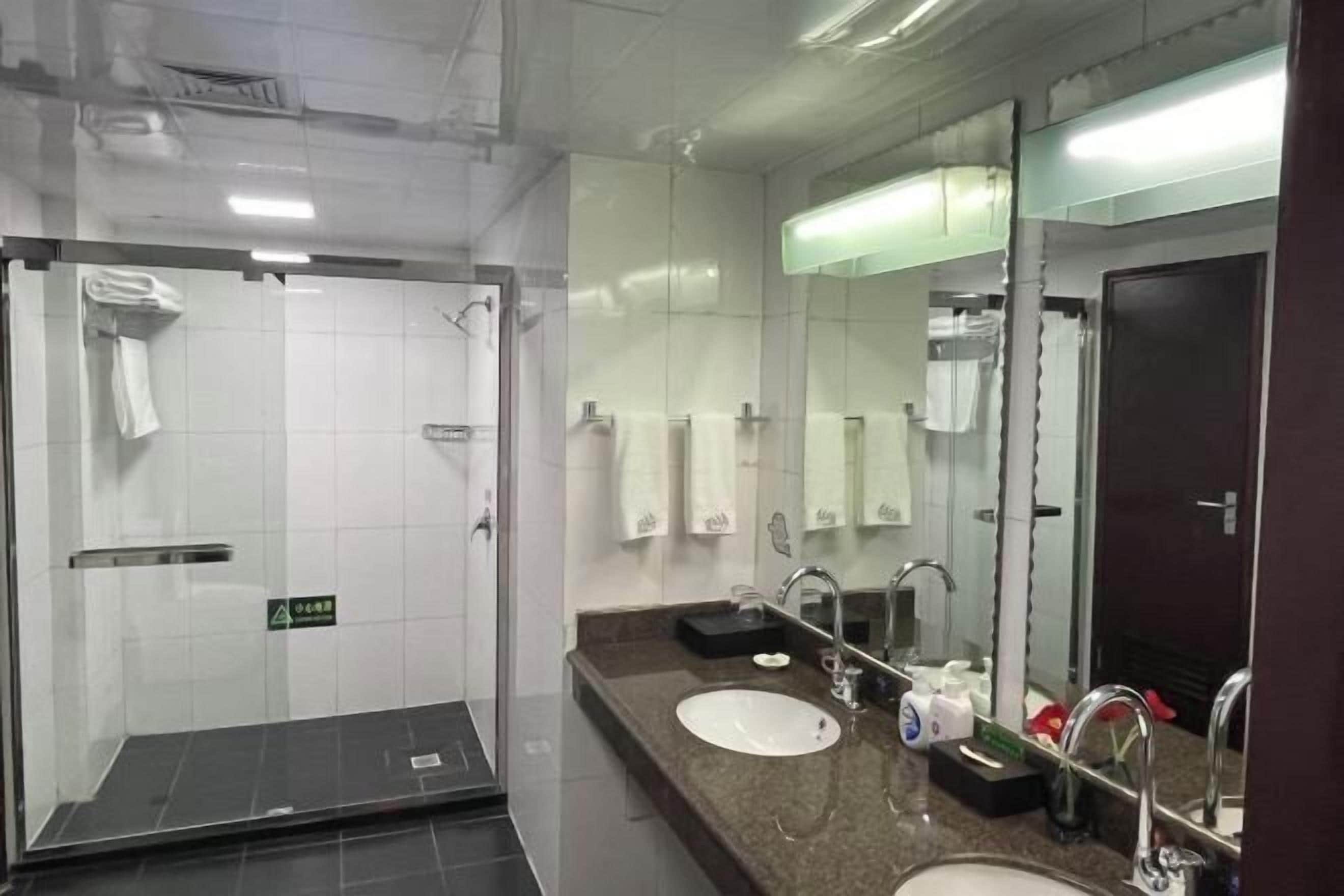 Une salle de bain moderne avec deux lavabos, un grand miroir et une douche à l’italienne.