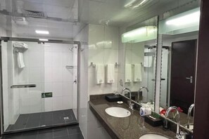 Ein modernes Badezimmer mit zwei Waschbecken, einem großen Spiegel und einer Duschkabine aus Glas.