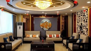 A modern living room with a central coffee table, two sofas, and a chandelier. - Bazhou Hotel (Urumqi)