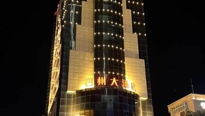 A tall hotel with a modern glass facade and illuminated signage. - Bazhou Hotel (Urumqi)