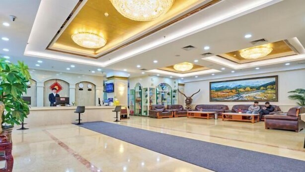 A spacious lobby with a reception desk, seating area, and a large painting on the wall. - Bazhou Hotel (Urumqi)