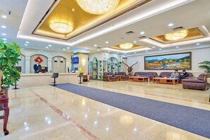 En hotellobby med en receptionsdisk, en sittgrupp och en stor målning på väggen.