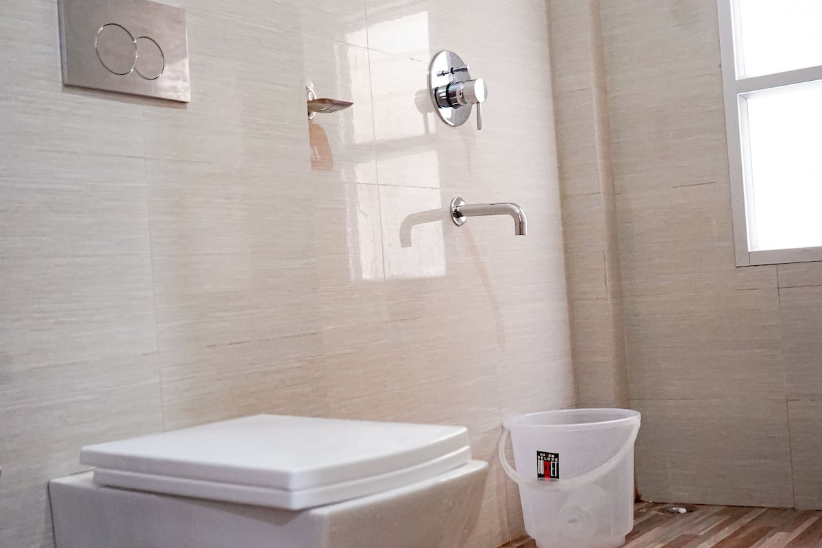 A bathroom with a toilet, a bidet, a shower, and a window.