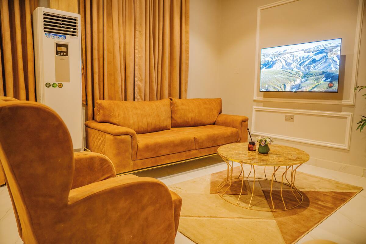 Ein Wohnzimmer mit einer Couch, einem Sessel und einem Couchtisch mit einer Vase.