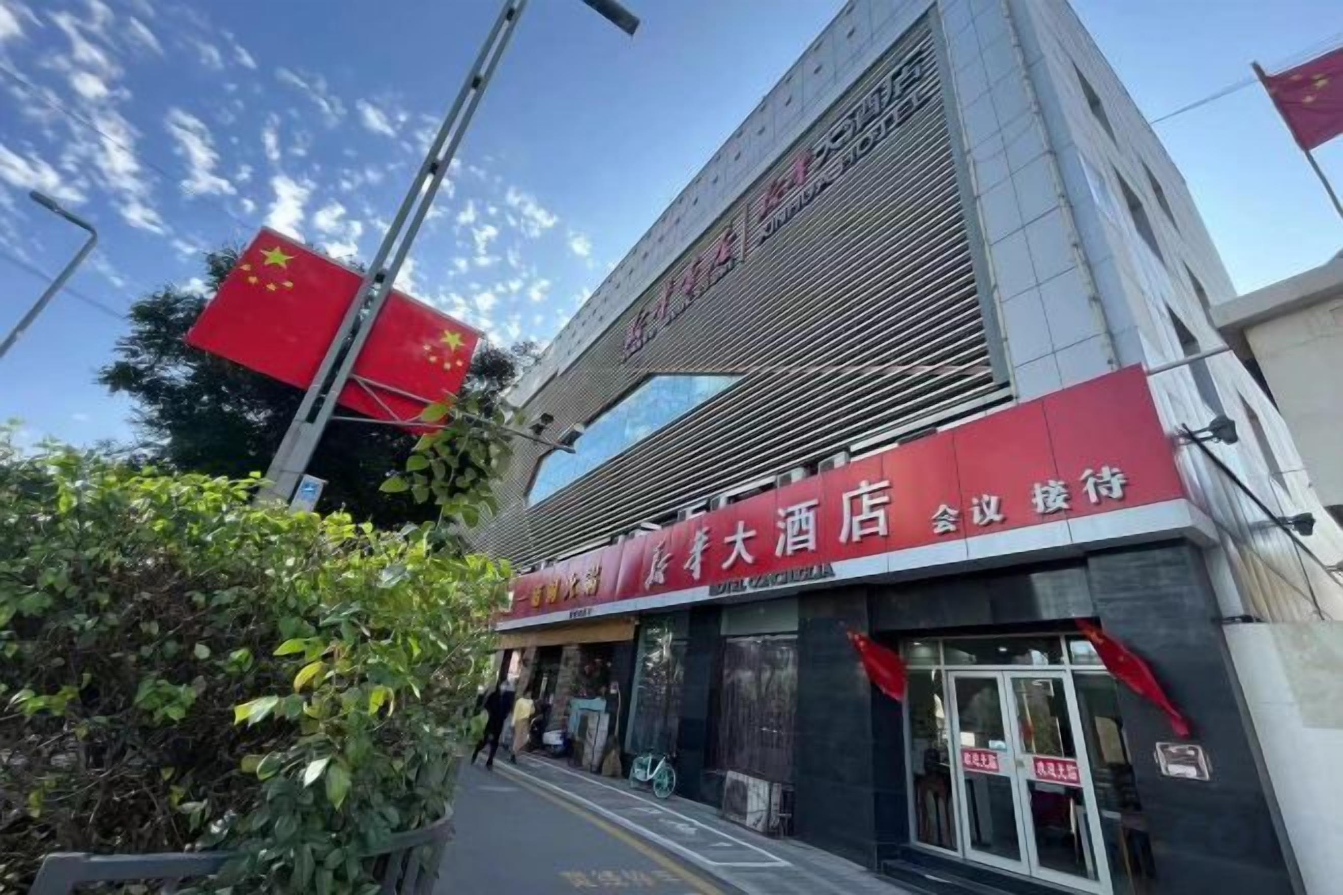 A hotel entrance with a red awning and signage, a clear sky, and a flag.