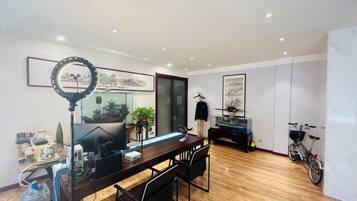 A modern dining area with a wooden table, chairs, and a ring light.