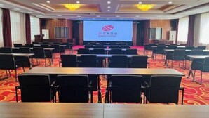 Une salle de conférence dotée d’une scène, de rangées de chaises et de lustres.