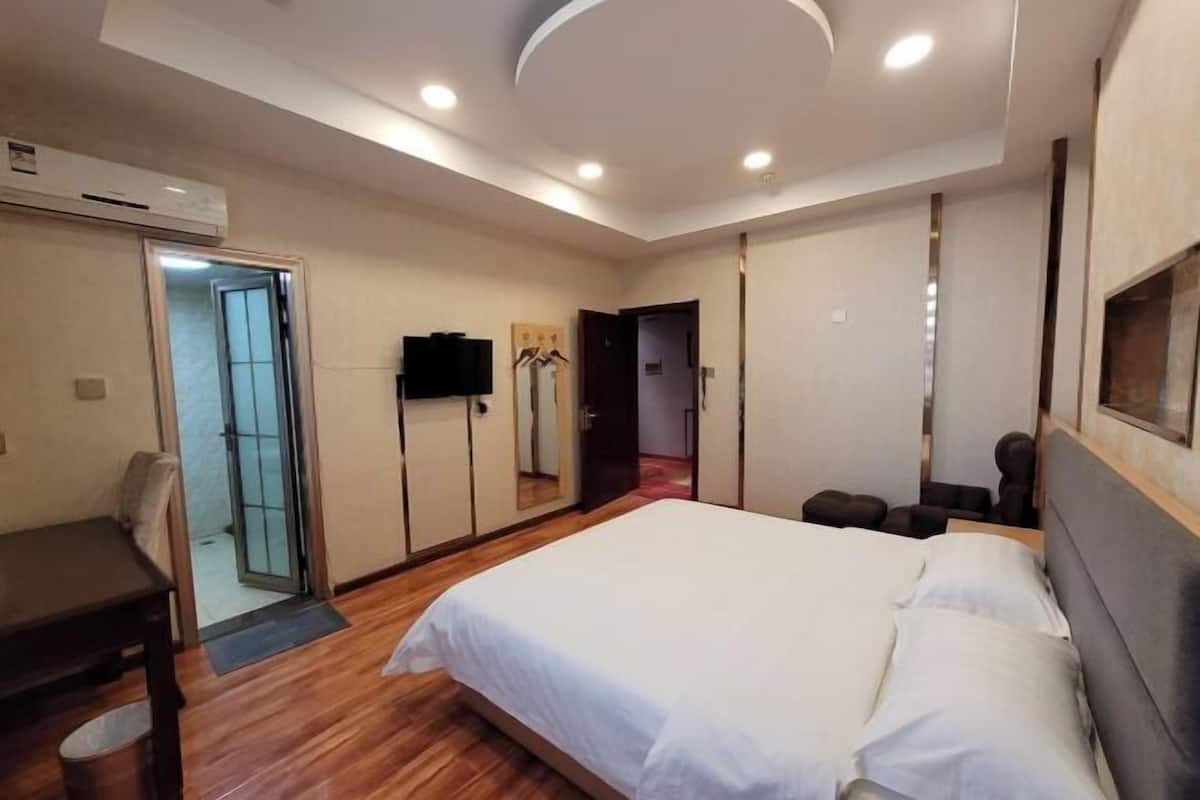 Un dormitorio con una cama, un escritorio, una silla, un televisor y un aire acondicionado.