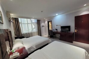 Een hotelkamer met twee bedden, een bureau met een televisie en een kledingkast.