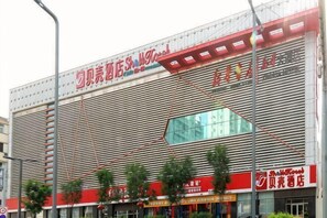 Een groot commercieel gebouw met verschillende etalages, waaronder een opvallend rood bord en een grote glazen pui.