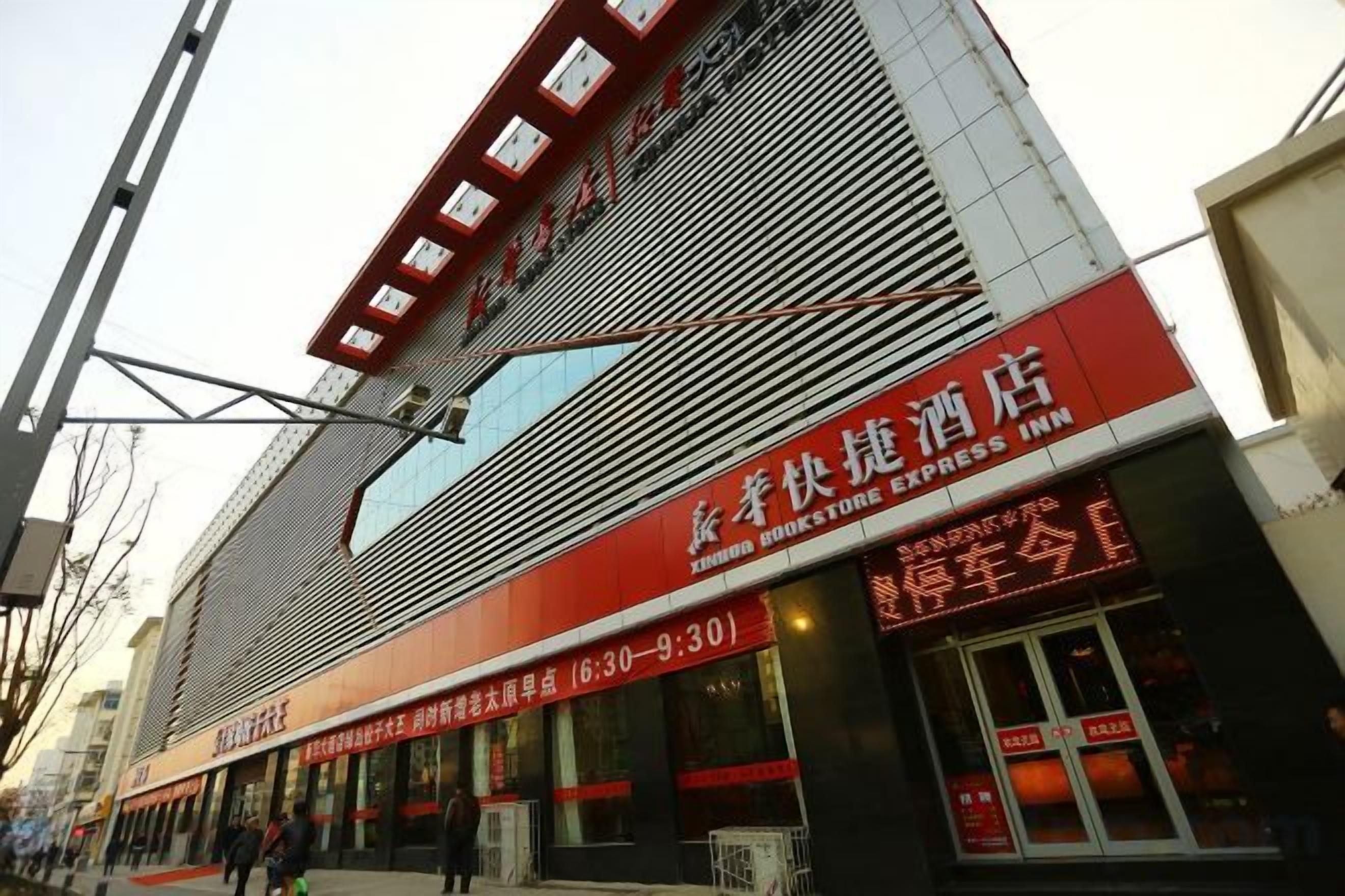 A hotel with a red and white facade, a visible entrance, and signage indicating a 24-hour service.