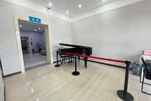 Une pièce avec un piano, une barrière délimitée par une corde rouge et un panneau indiquant le numéro de la pièce.