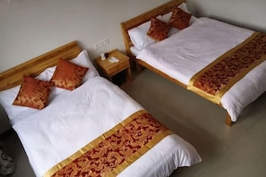 Two twin beds with wooden headboards, white bedding, and red decorative pillows.