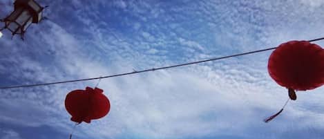 Ein klarer Himmel mit Wolken und zwei rote Laternen, die an einem Draht hängen.