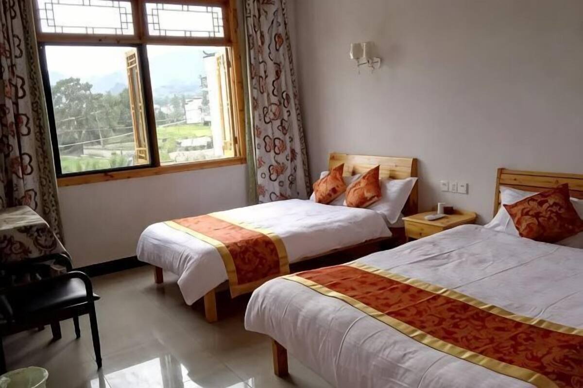 Une chambre d’hôtel avec deux lits, un bureau et une fenêtre avec des rideaux.