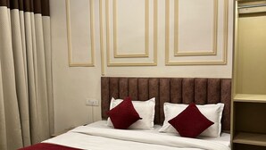 A hotel room with a large bed, a ceiling fan, and a wardrobe. - Sri Madhav Stay (Varanasi)