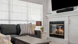 En moderne stue med en grå sofa, et sofabord og en pejs.