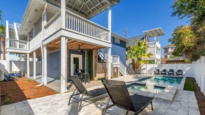 Et toetagers hus med en overdækket terrasse, swimmingpool og udendørs møbler.