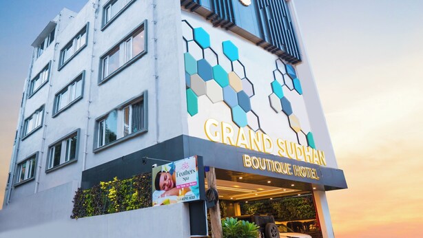 Un edificio con un cartel que dice 'Grand Suphan Boutique Hotel' y un spa llamado 'Feathers Spa'.