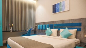 Una habitación de hotel moderna con una cama grande, un escritorio con una silla, un florero con flores y un cuadro en la pared.
