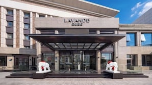 A modern hotel entrance with a covered entrance area, glass doors, and a name sign.