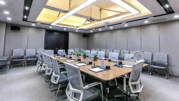 A conference room with a long table, chairs, and a ceiling light fixture.
