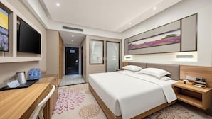 A hotel room with a bed, desk, and a television.