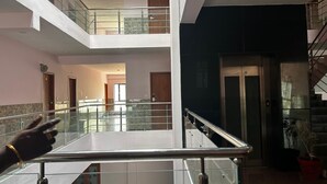A multi-level interior with glass railings, a central open space, and a staircase. - J V Residency (Salem)