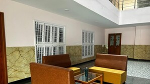 A lobby with a marble wall, two windows with bars, and a wooden door. - J V Residency (Salem)