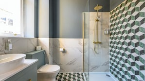 Un baño moderno con ducha de vidrio, lavabo de mármol y retrete.
