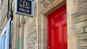 Un edificio con puerta roja y un letrero que dice 'Deuce Hotel'.