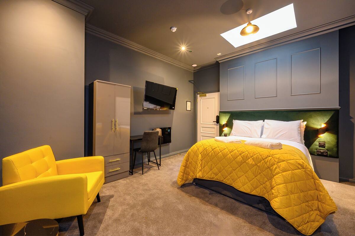 A bedroom with a bed, a desk, a chair, and a wardrobe.