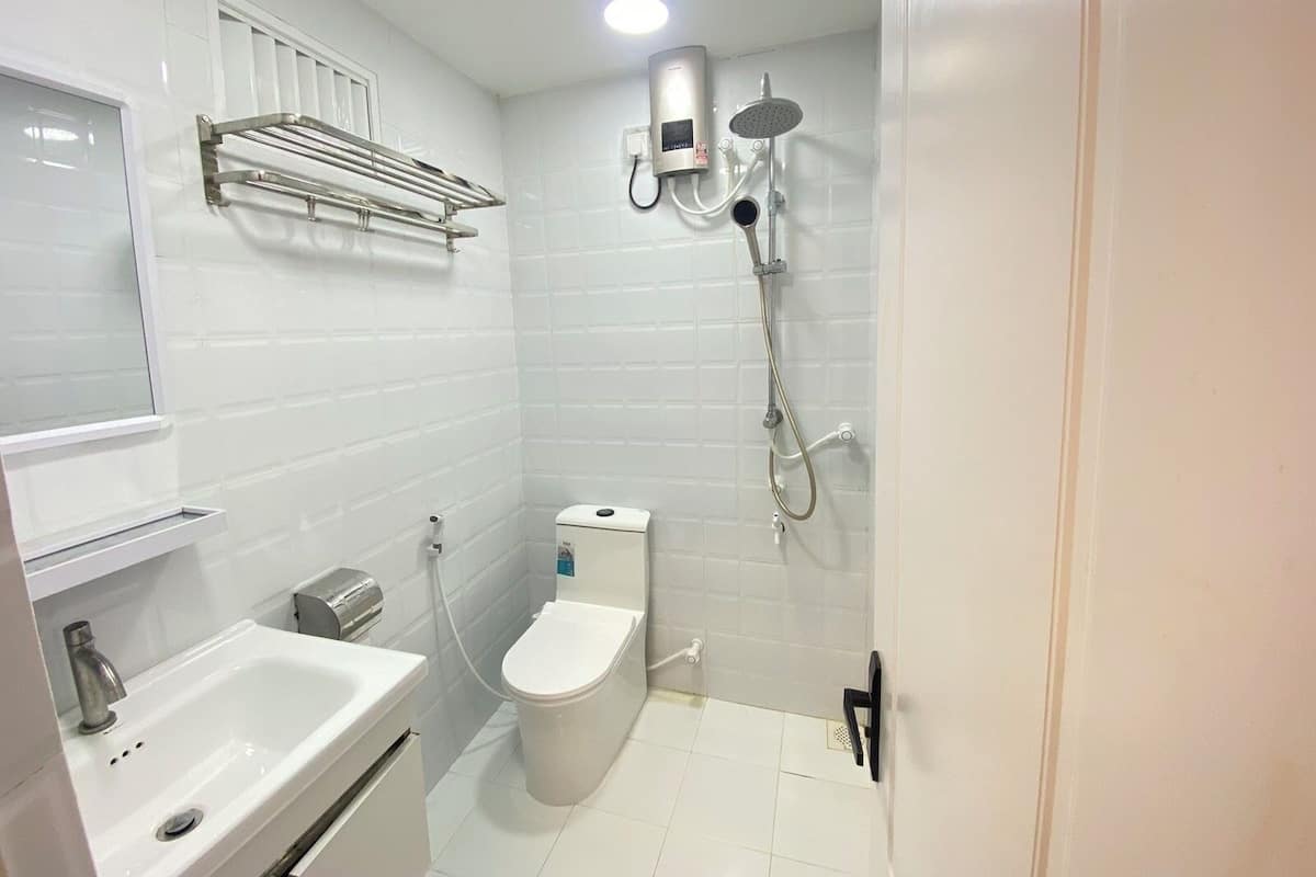 A modern bathroom with a white sink, toilet, and shower.