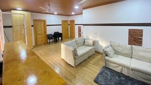 A spacious living area with two sofas, a wooden table, and ceiling fans. - Ever Blue Guest House (Mathiveri)