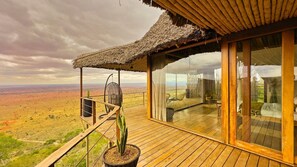 A wooden deck with a thatched roof, a hanging chair, and a potted plant. - Soroi Lions Bluff Lodge (Maktau)