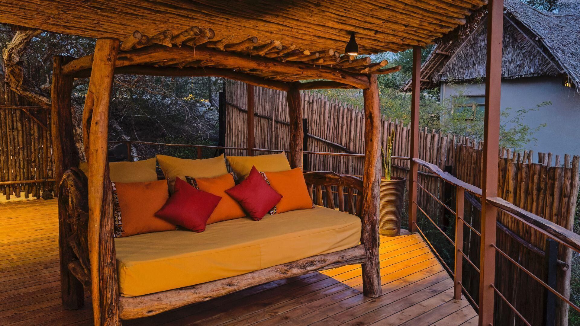 A wooden bed with cushions on a deck.