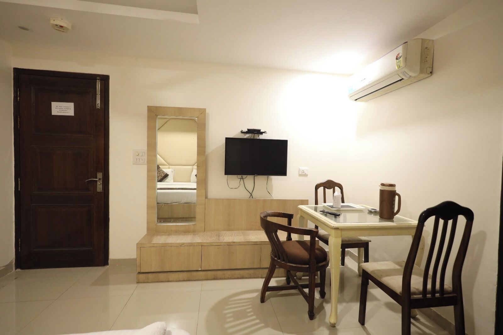Une chambre d’hôtel équipée d’un lit, d’un téléviseur fixé au mur, d’une table avec des chaises et d’un appareil de climatisation.