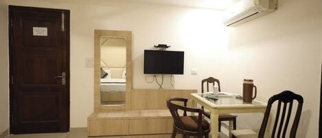 Une chambre d’hôtel équipée d’un lit, d’un téléviseur fixé au mur, d’une table avec des chaises et d’un appareil de climatisation.