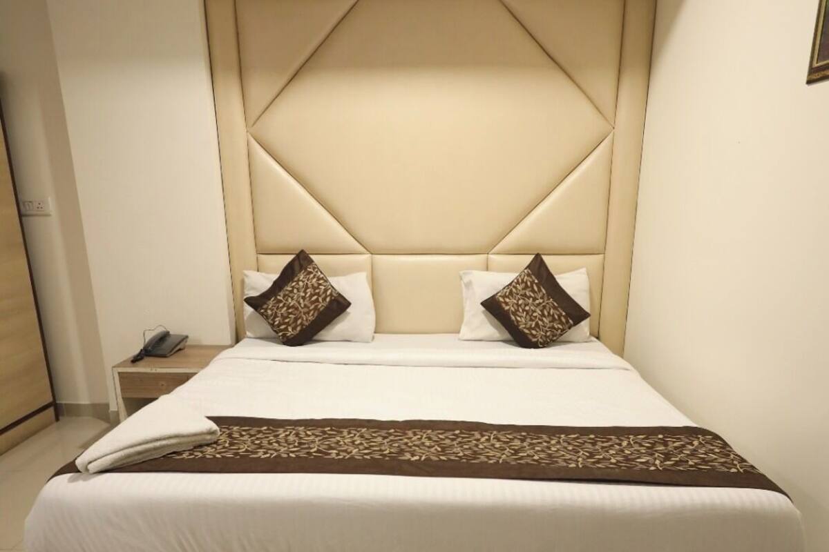 Ein Schlafzimmer mit einem großen Bett, einem Kopfteil mit geometrischem Muster und einem Nachttisch mit Lampe.