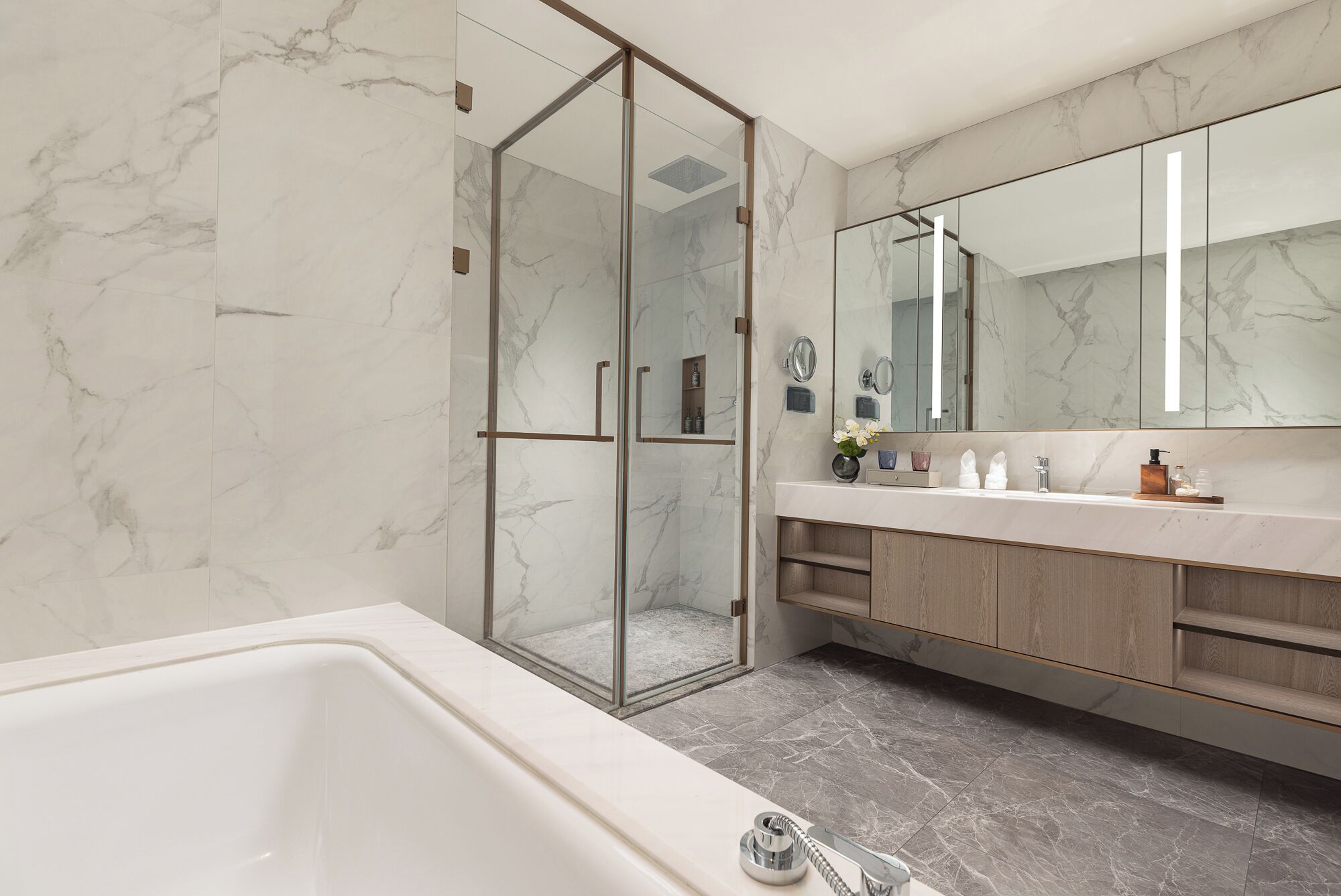 A modern bathroom with a glass-enclosed shower, a large mirror, and a bathtub.