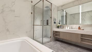 Un baño moderno con ducha de vidrio, un espejo grande y una bañera.