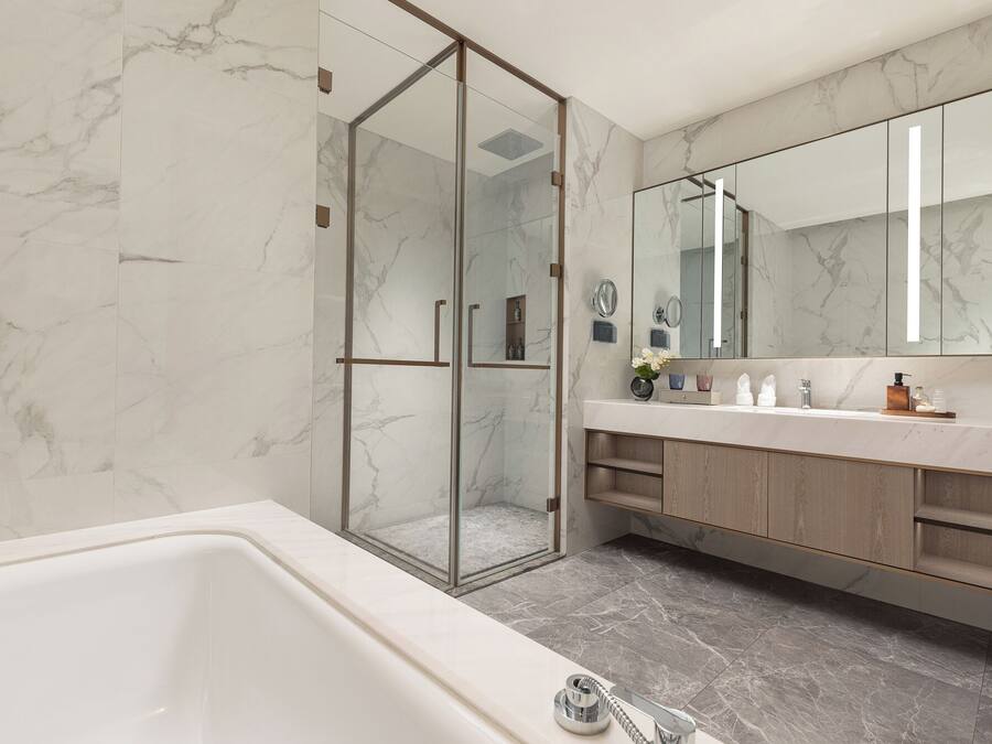 Un baño moderno con ducha de vidrio, un espejo grande y una bañera.