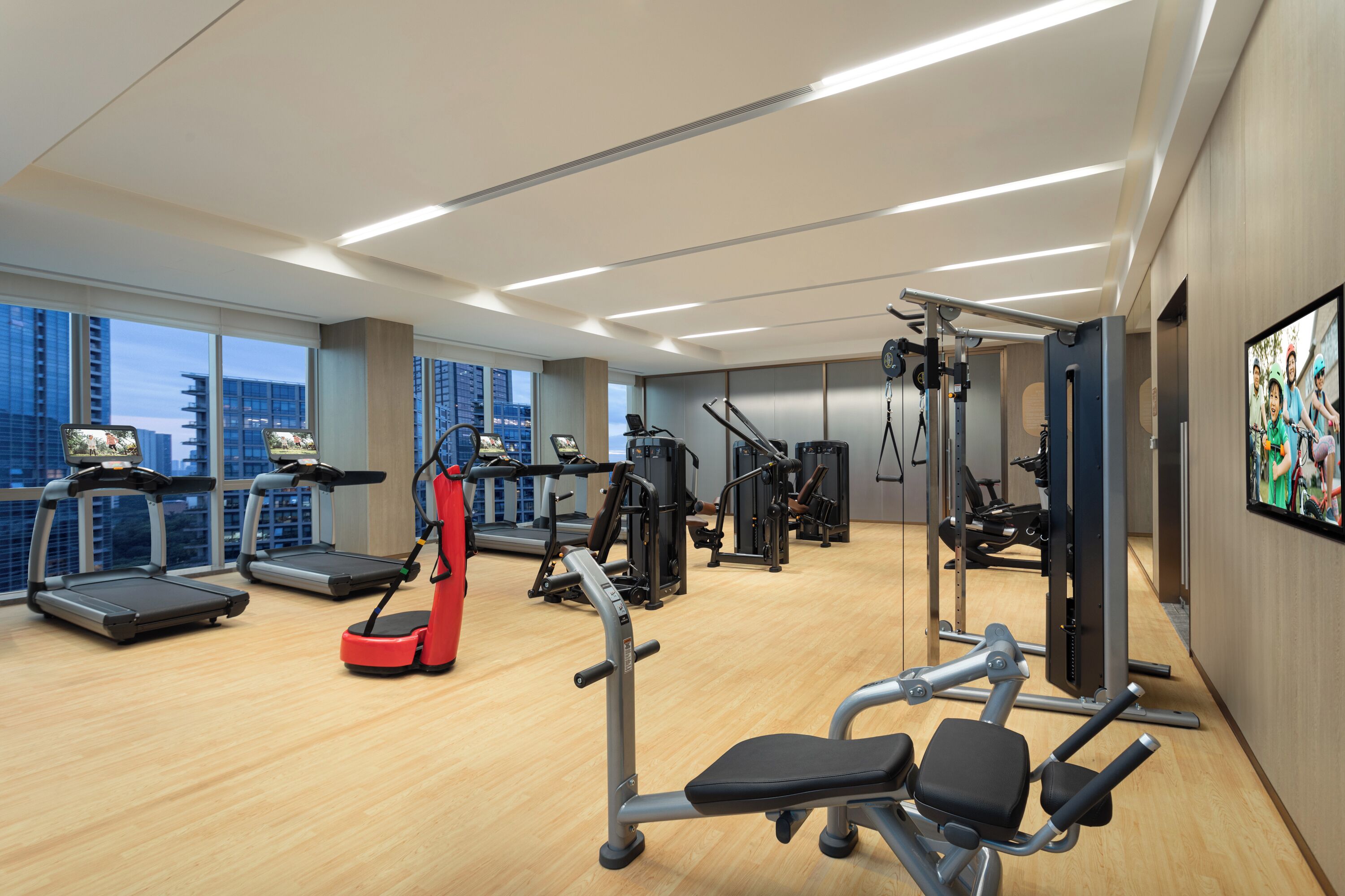A modern gym with treadmills, weight machines, and a red exercise bike.